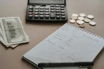 A calculator, money and calculations in a notebook — illustration for an article about the HR automation budget