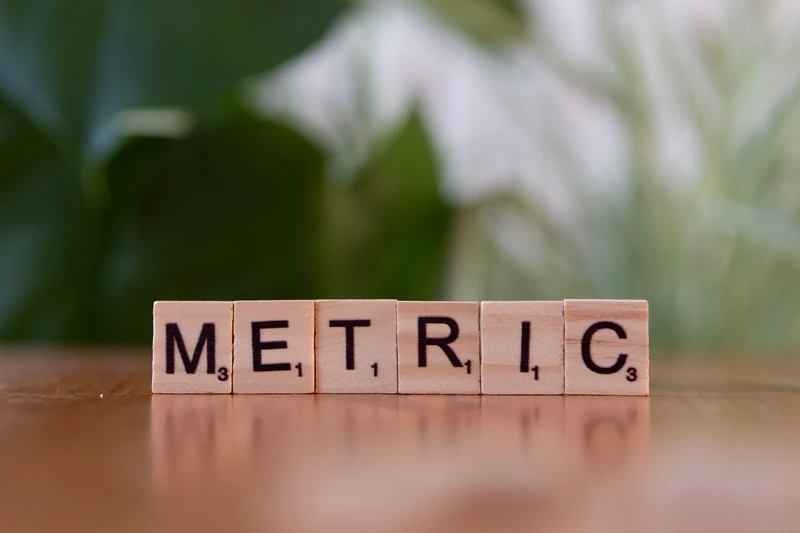 Wooden letters spelling METRIC against greenery — illustration for an article about evaluating employee performance