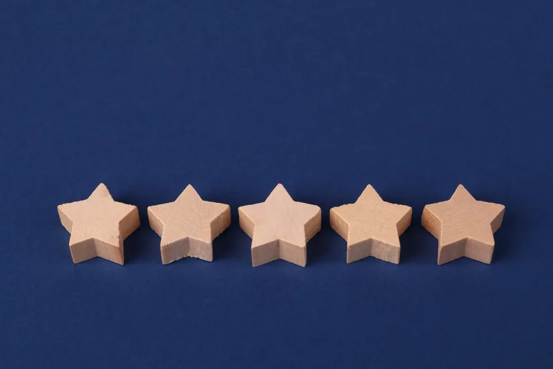 Five wooden stars in a row on a dark blue background — illustration for an article about running a 360-degree review