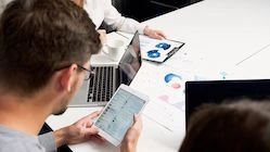 A team studying charts on a tablet and laptop — illustration for an article about choosing an HR solution