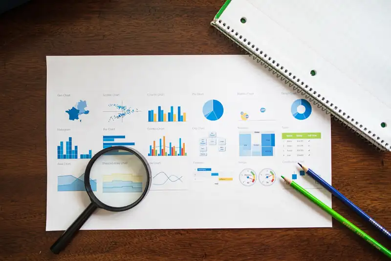 A sheet with KPI charts and graphs on a desk with a magnifier and pencils — illustration for an article about cascading goals