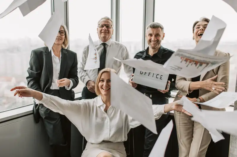 A team in the office happily tossing papers into the air — illustration for an article about the cost of employee turnover